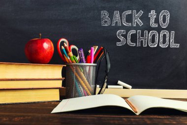 Yazma malzemeleri, bir kitap ve bir elma, metin için boş veya bir okul teması için bir arka plan ile Öğretmen masası. Kopyalama alanı.
