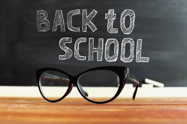 bir masada gözlük öğretmen, tebeşir ile bir tebeşir arka plan karşı. Öğretmenler günü için konsept. Kopyalama alanı.