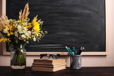 Öğretmenler günü geçmişi. Siyah tebeşir tahtası boş kopya alanı ve vazo da taze kır çiçekleri. Tatil kadınsı posteri. Bahar tebrik 8 mart simgesi.