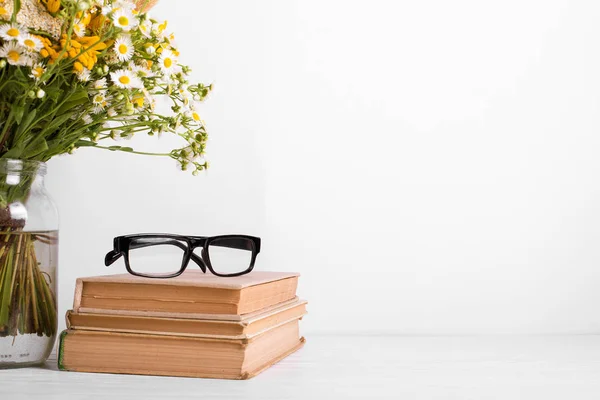 Ramo de verano de flores silvestres en jarrón de vidrio, libros antiguos sobre fondo rústico. Concepto de diseño de temporada. Concepto del día del maestro, de vuelta a la escuela . — Foto de Stock