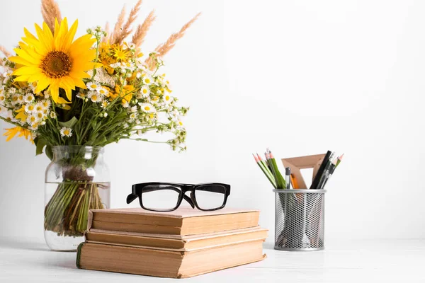 Buquê de verão de flores silvestres em vaso de vidro, livros antigos sobre fundo rústico. Conceito de design de temporada. Conceito do dia dos professores, de volta à escola . — Fotografia de Stock