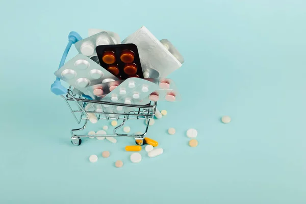 Καλάθι αγορών φορτωμένο με χάπια σε μπλε φόντο. Η έννοια της ιατρικής και την πώληση των ναρκωτικών. Χώρο αντίγραφο. — Φωτογραφία Αρχείου