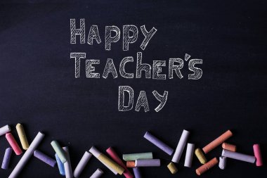 Çok renkli boya kalemleri siyah bir tebeşir tahtası üzerinde yatıyor, kopya alanı. Okul, eğitim ve çocukluk kavramı.