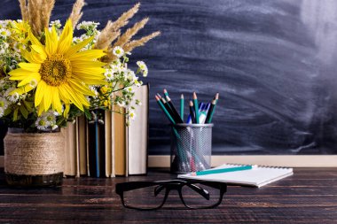 Kitaplar, gözlükler, işaretler ve beyaz tahta arka plan üzerinde bir vazo çiçek bir buket. Öğretmenler günü ve ilk Eylül için kavram. Kopyalama alanı.