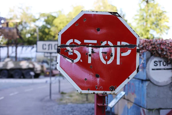 STOP road sign, at the scene of hostilities. Bullet holes in metal.
