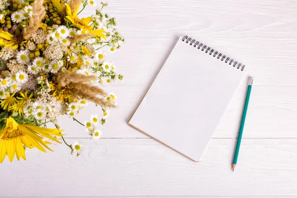 Buquê de flores, caderno e lápis em uma mesa branca. Espaço de cópia . — Fotografia de Stock