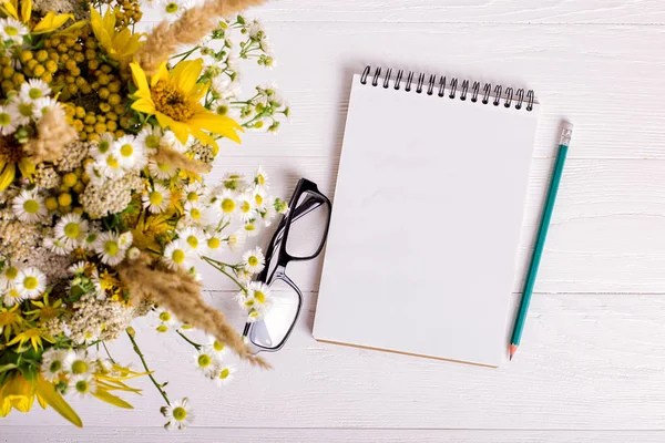 Buquê de flores, caderno e lápis em uma mesa branca. Espaço de cópia . — Fotografia de Stock