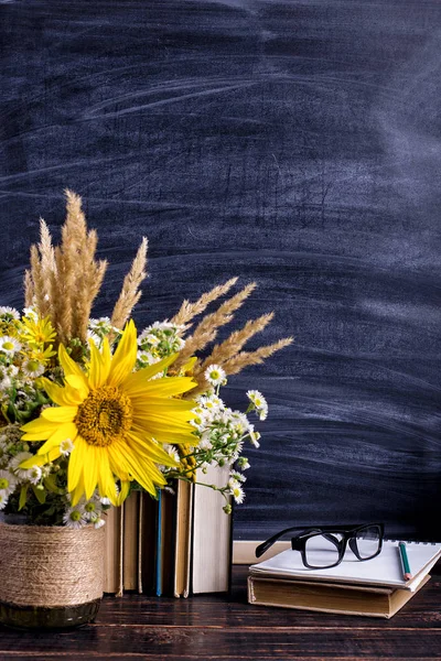 Книги, очки, маркеры и букет цветов в вазе на белом фоне доски. Концепция дня учителя и первого сентября. Копирование пространства . — стоковое фото