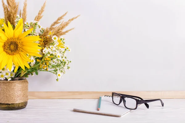 Libros, vasos, marcadores y un ramo de flores en un jarrón sobre fondo de pizarra blanca. Concepto para el día del profesorado y primer septiembre. Copiar espacio . — Foto de Stock