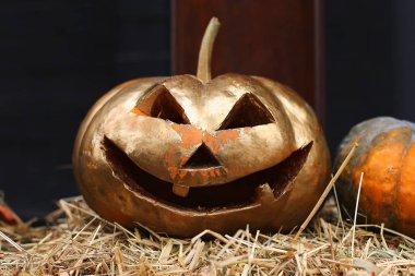 Oyma suratlı kabaklar samanların içinde yatıyor. Cadılar Bayramı hazırlık, rustik tarzı.