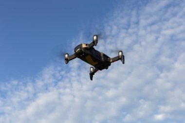 Bir drone, video çekimi için bir kamera ile bir quadrocopter, bulutlar ile mavi bir gökyüzüne karşı uçar.