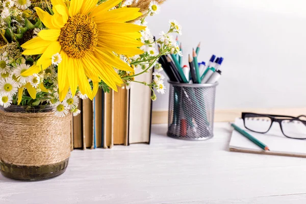 Buku, kacamata, penanda dan karangan bunga dalam vas di latar papan putih. Konsep untuk hari guru dan September pertama. Salin ruang . — Stok Foto