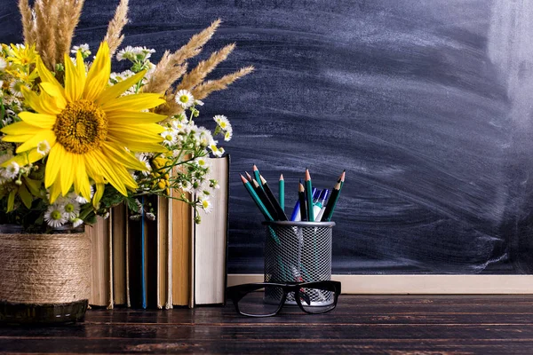 Books, glasses, markers and a bouquet of flowers in a vase on white board background. Concept for teachers day and first September. Copy space.