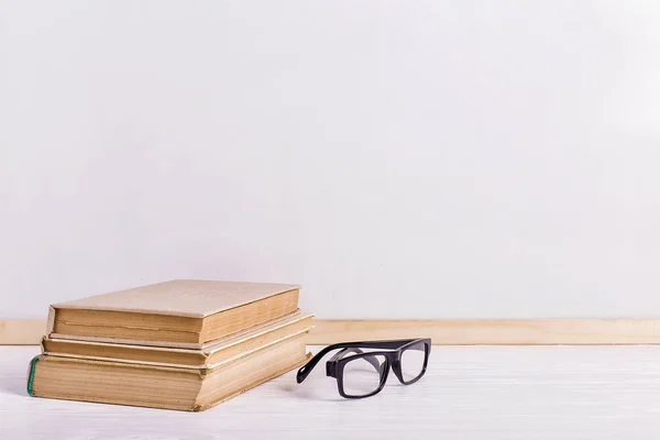 Libri e bicchieri sul tavolo sullo sfondo di una lavagna bianca. Copia spazio . — Foto Stock