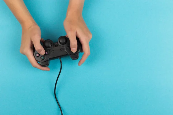 Frauenhände halten ein Gamepad auf blauem Hintergrund. Wochenendkonzept, Gaming-Hobby. Kopierraum. — Stockfoto
