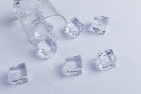 Empty inverted fallen glass with ice, on a white background. — Stock Photo, Image