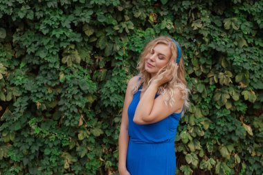 Mavi kulaklıkmüzik dinlerken bir elbise güzel genç sarışın kız. Gerçek hayat, anın tadını çıkar. Kopyalama alanı.