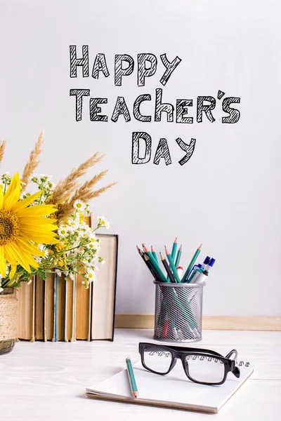 Buquê de flores e cadernos com óculos na mesa. A inscrição dia de professor feliz .. — Fotografia de Stock