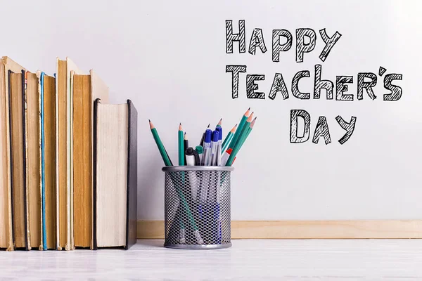 Penanda prasasti di papan putih, Selamat Hari Guru. Sebuah meja dengan buku, kacamata dan atribut untuk menulis . — Stok Foto
