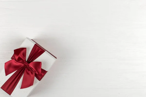Cadeau avec un ruban rouge et un arc sur fond blanc, espace de copie . — Photo