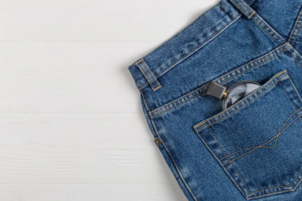 Bottiglia di profumo o acqua di toletta in una tasca di jeans blu . — Foto Stock