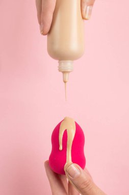 Kız el temel güzellik blender tutar, pembe arka plan üzerinde kapatıcı. Makyaj sanatçısı kavramı, kopyalama alanı.