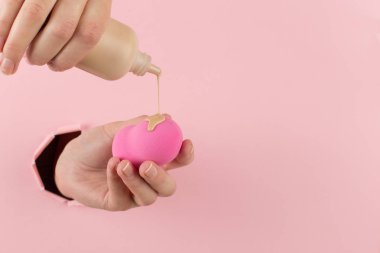 Kız el temel bir güzellik blender tutar, pembe bir arka plan bir delik kapatıcı. Makyaj sanatçısı kavramı, kopyalama alanı.