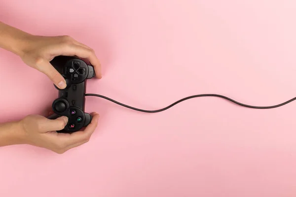 Frauenhände halten ein Gamepad auf rosa Hintergrund. Wochenendkonzept, Gaming-Hobby. Kopierraum. — Stockfoto