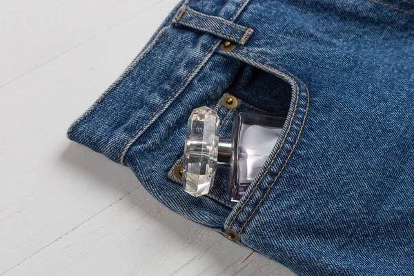 Bottiglia di profumo o acqua di toletta in una tasca di jeans blu . — Foto Stock