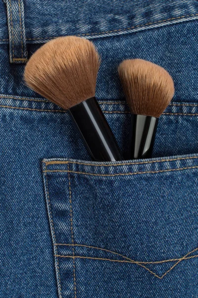 Large makeup brushes in a pocket of blue jeans. Concept, commercial work of a makeup artist, for printing business cards and brochures.