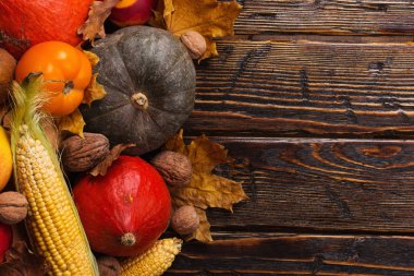 Farklı sebzeler, kabaklar, elma, armut, fındık, domates, mısır, ahşap arka plan üzerinde kuru sarı yaprakları. Sonbahar havası, kopya alanı. Hasat konsepti.