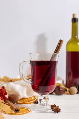 Masada baharat, şişe, atkı, baharat, kuru yaprak ve portakal ile mulled şarap bir fincan. Sonbahar ruh hali, soğuk sıcak tutmak için yöntem, kopya alanı.