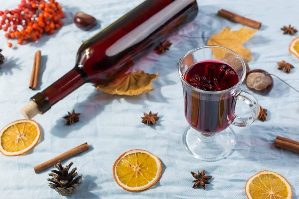 Una taza de vino caliente con especias, botella, hojas secas y naranjas —  Fotos de Stock