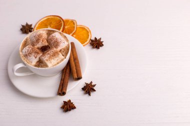 Beyaz bir arka plan üzerinde marshmallow ve kakao, yaprakları, kurutulmuş portakal, baharat, kahve fincan. Lezzetli sıcak sonbahar içeceği, sabah havası. Kopyalama alanı.