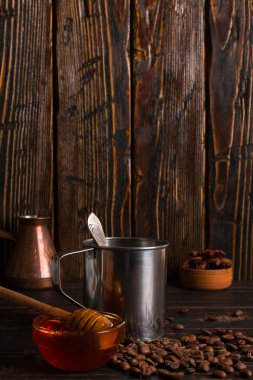 Ahşap bir t üzerinde siyah kahve, bal ve kahve çekirdekleri ile Demir kupa