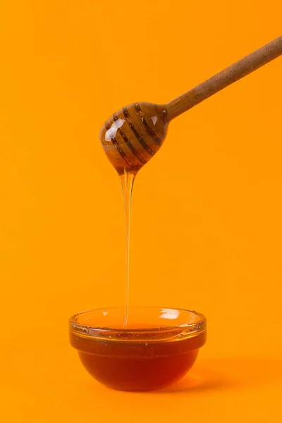 Un palo para la miel y un frasco pequeño, concepto sobre un fondo amarillo — Foto de Stock