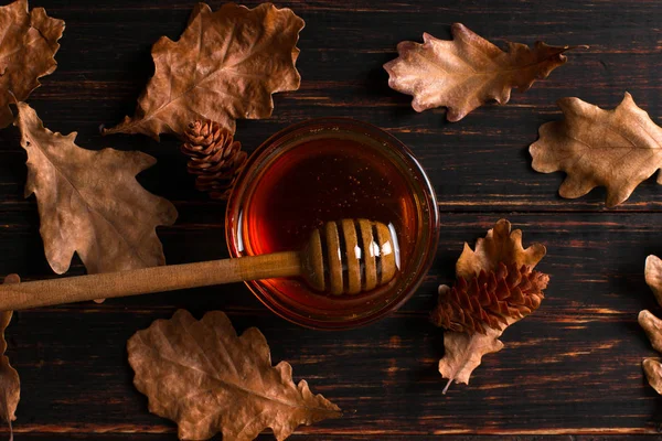 Honey flows from a stick into a jar. Rustic sweet autumn photo,