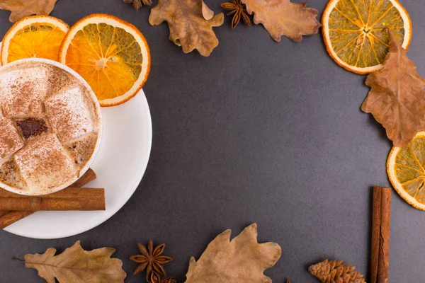 Taza de café con malvaviscos y cacao, hojas, naranjas secas, canela y anís estrellado, fondo de piedra gris. Sabrosa bebida caliente de otoño. Copiar espacio . —  Fotos de Stock