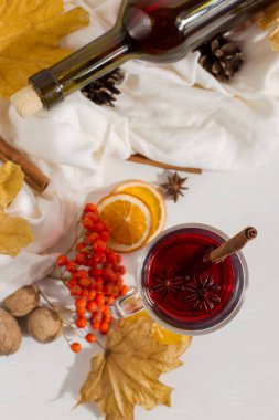 Masada baharat, şişe, atkı, baharat, kuru yaprak ve portakal ile mulled şarap bir fincan. Sonbahar ruh hali, soğuk sıcak tutmak için yöntem, kopya alanı.
