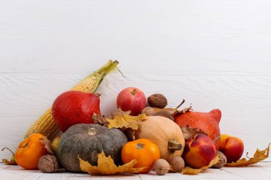 Farklı sebzeler, kabaklar, elma, armut, fındık, mısır, domates ve kuru yapraklar beyaz ahşap arka plan üzerinde. Sonbahar Hasat kavramı, kopya alanı.