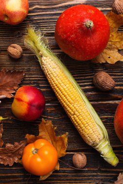 Farklı sebzeler, kabaklar, elma, armut, fındık, domates, mısır, ahşap arka plan üzerinde kuru sarı yaprakları. Sonbahar havası, düz yatıyordu. Hasat konsepti.