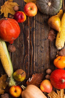 Farklı sebzeler, kabaklar, elma, armut, fındık, domates, mısır, ahşap arka plan üzerinde kuru sarı yaprakları. Sonbahar havası, kopya alanı. Hasat konsepti.