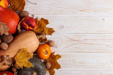 Farklı sebzeler, kabaklar, elma, armut, fındık, domates ve kuru yaprakları beyaz ahşap arka plan üzerinde. Sonbahar havası, kopya alanı. Hasat konsepti.