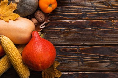 Farklı sebzeler, kabaklar, elma, armut, fındık, domates, mısır, ahşap arka plan üzerinde kuru sarı yaprakları. Sonbahar havası, kopya alanı. Hasat konsepti.