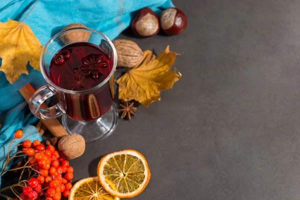 Copa de vino caliente con especias, una bufanda, hojas secas y naranjas en una mesa de piedra. El estado de ánimo otoñal, un método para mantener el calor en el frío, copiar el espacio . —  Fotos de Stock