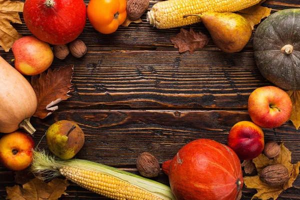 Different vegetables, pumpkins, apples, pears, nuts, tomatoes, corn, dry yellow leaves on wooden background. Autumn mood, copy space. Harvest concept. — Stock Photo, Image