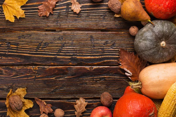 Différents légumes, citrouilles, pommes, poires, noix, tomates, maïs, feuilles jaunes sèches sur fond en bois. Humeur d'automne, espace de copie. Concept de récolte . — Photo