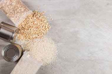 Yiyecek malzemeleri, yulaf ezmesi kavanozları ve konserve pirinç, yukarıdan bakıldığında, taş bir tezgahın üzerinde..
