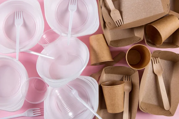 Pembe arka planda plastik ve kağıt çatal bıçaklar. Çevre dostu aletler seçmek, ekolojik felaketlerle savaşmak..