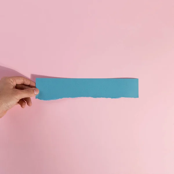 Ein Streifen Zerrissenes Blaues Papier Der Hand Auf Rosa Hintergrund — Stockfoto